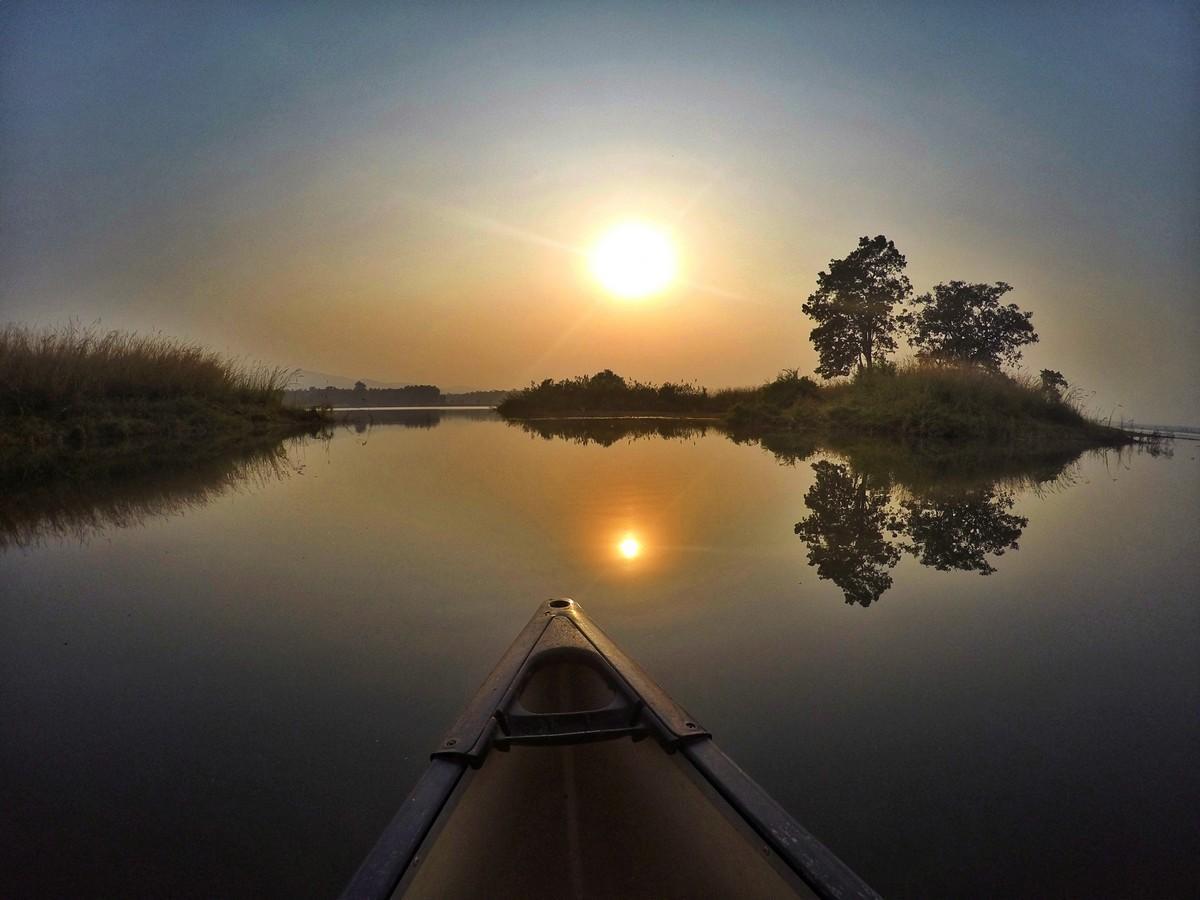 the tip of a canoe on the river at sunset