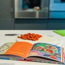 cookbook and chorizo and knife on a chopping board