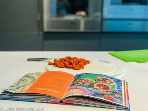 cookbook and chorizo and knife on a chopping board