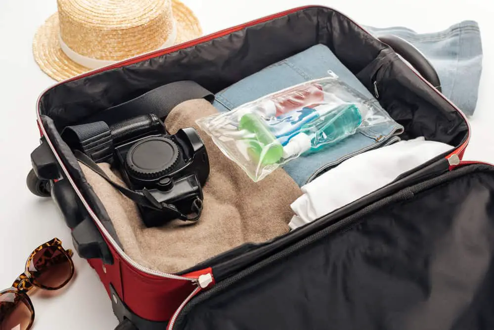 a suitcase packed with clothes, toiletries an a camera